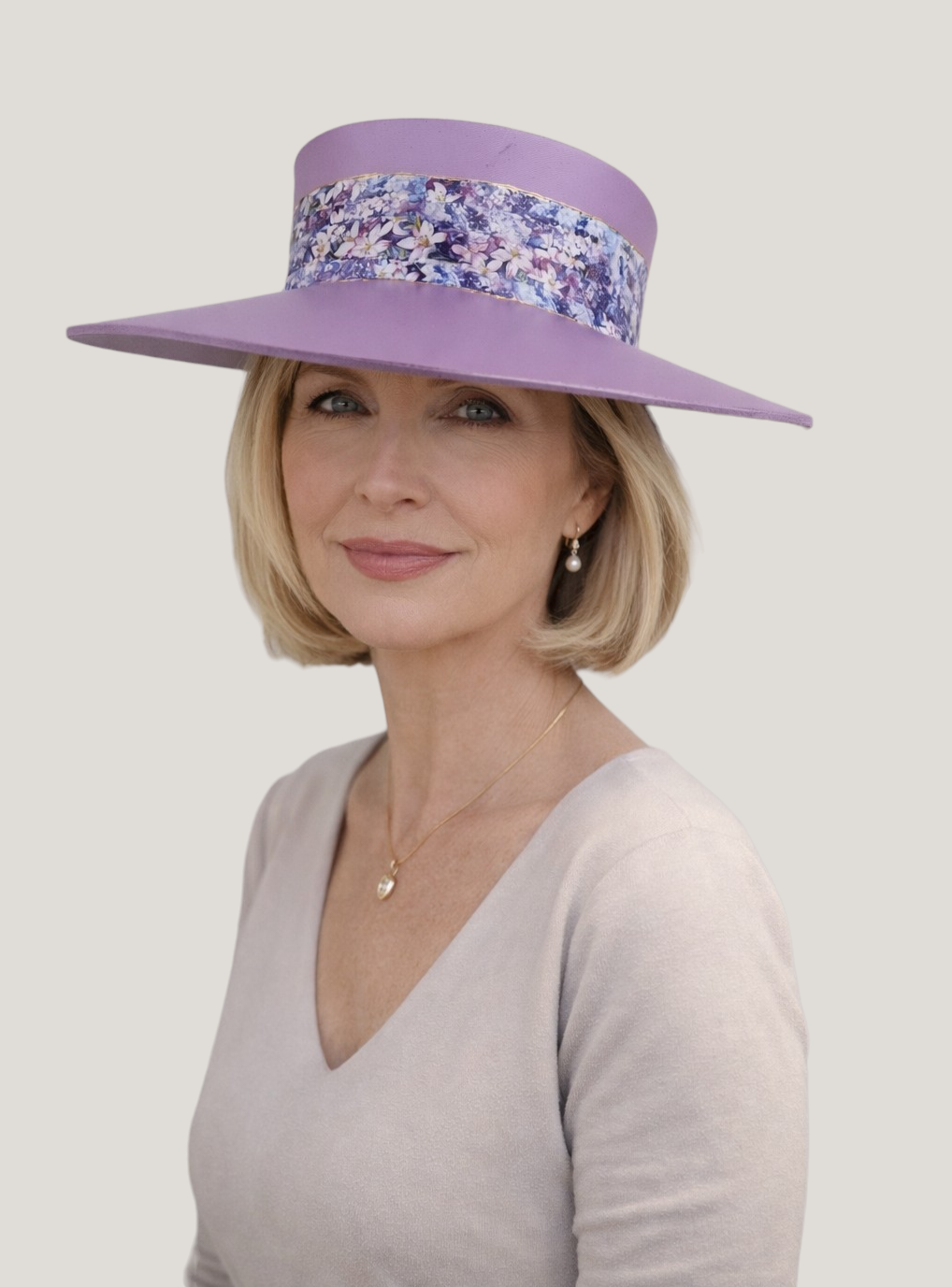 Woman wearing a wide-brimmed purple hat with floral band on a plain background