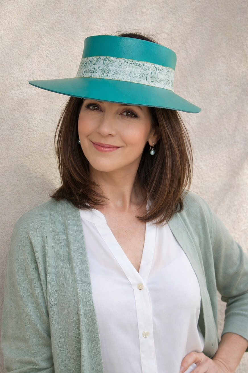 Woman wearing a teal visor against a neutral background