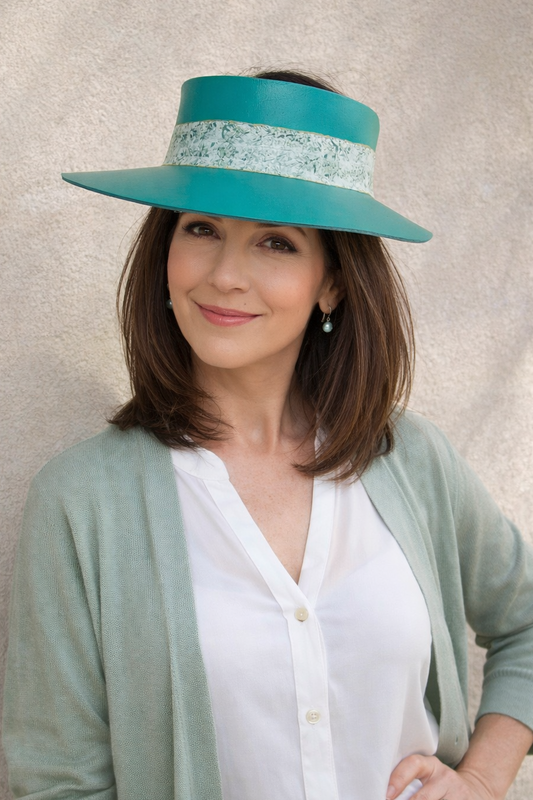 Woman wearing a teal visor against a neutral background