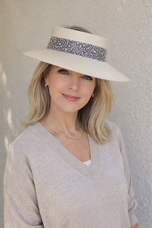 Woman wearing a white sun hat with a decorative band against a light background
