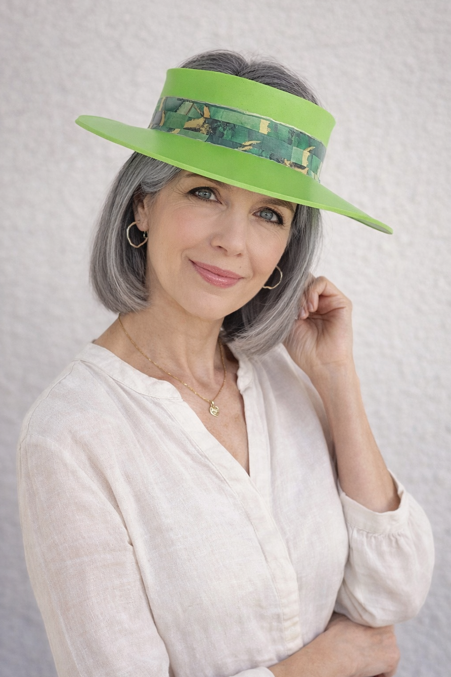 Woman wearing a green visor with floral pattern on a gray background