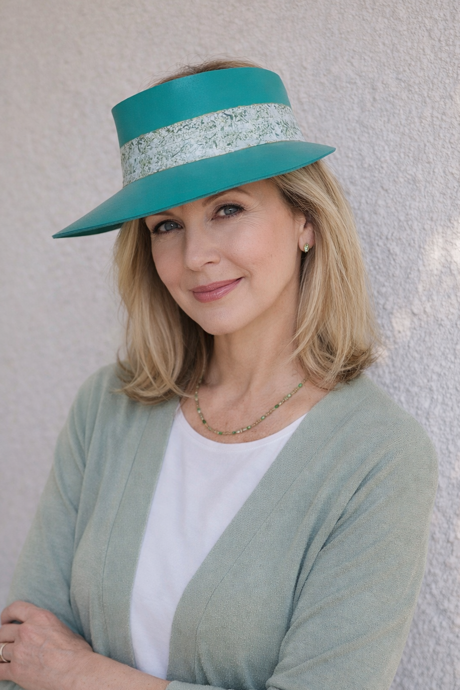 Woman wearing a teal hat with a white band against a light background