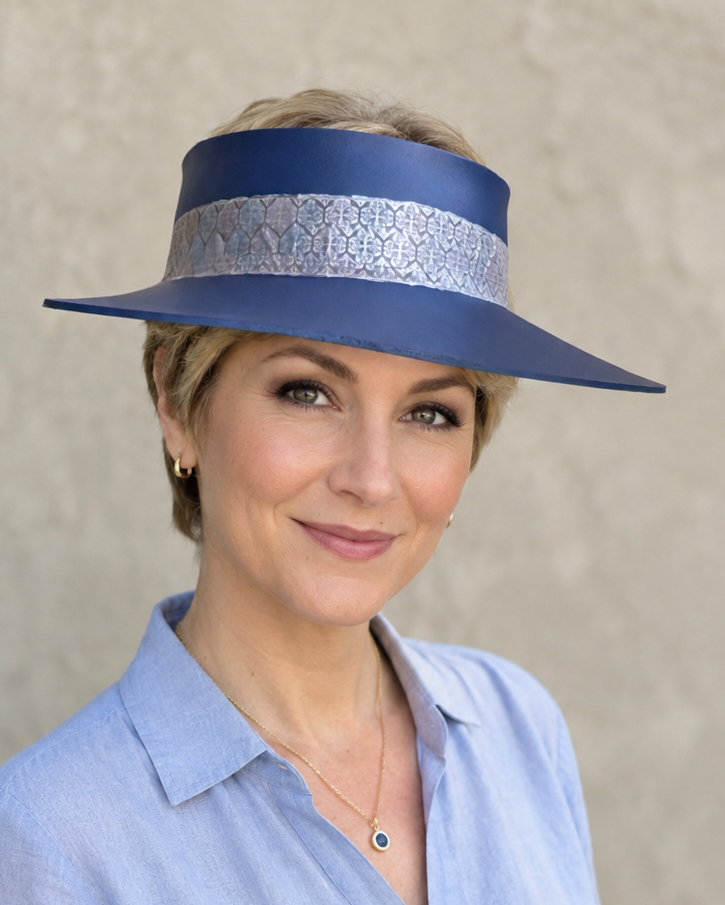 Woman wearing a blue hat with a decorative band against a plain background
