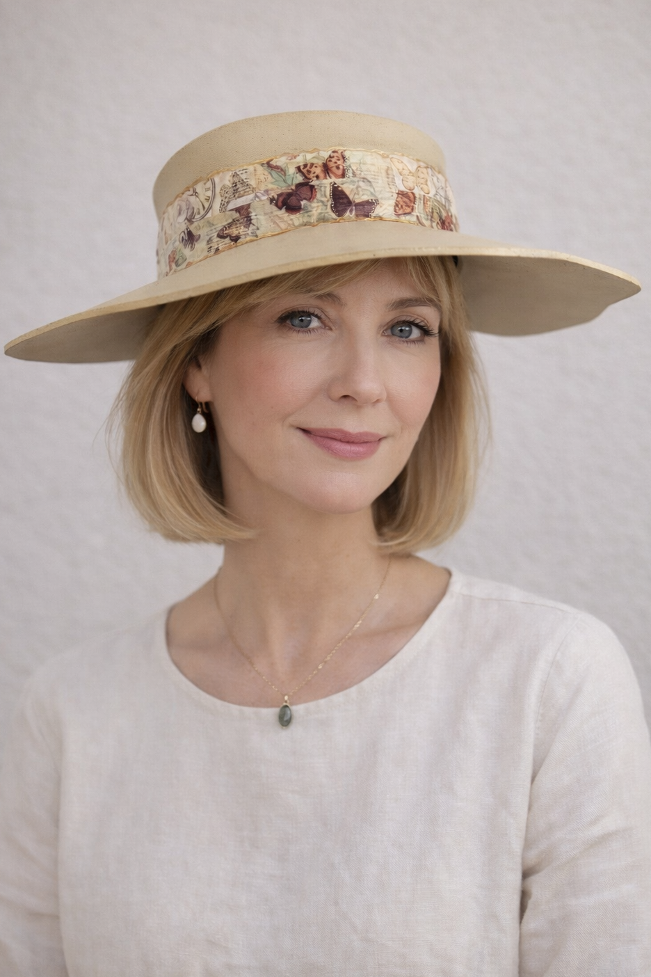 Woman wearing a beige hat with a floral band against a plain background
