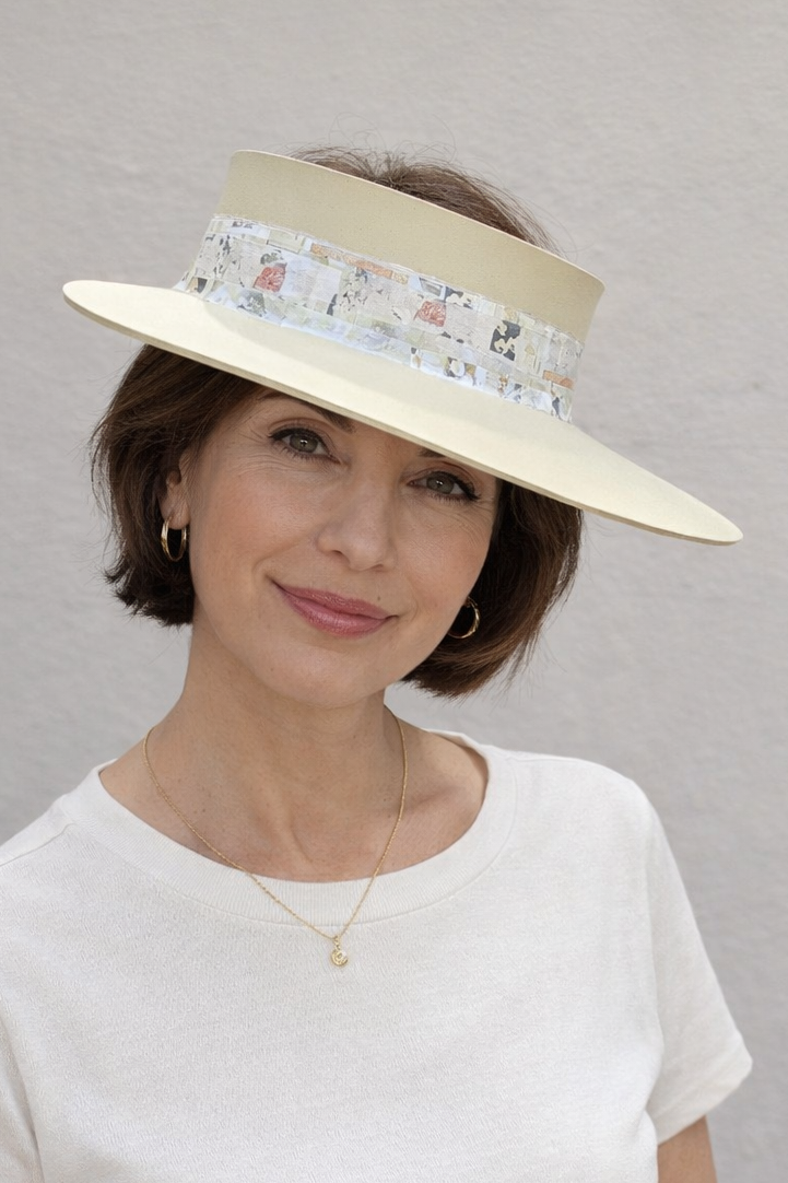 Woman wearing a white hat with a floral band against a gray background