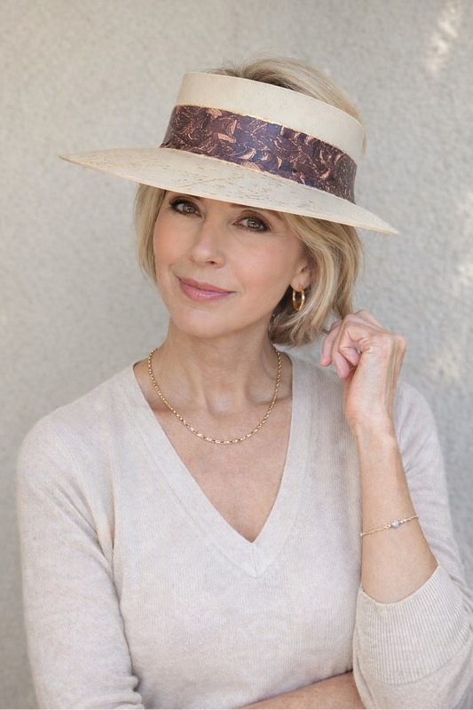 Woman wearing a wide-brimmed hat with a decorative band against a textured white background