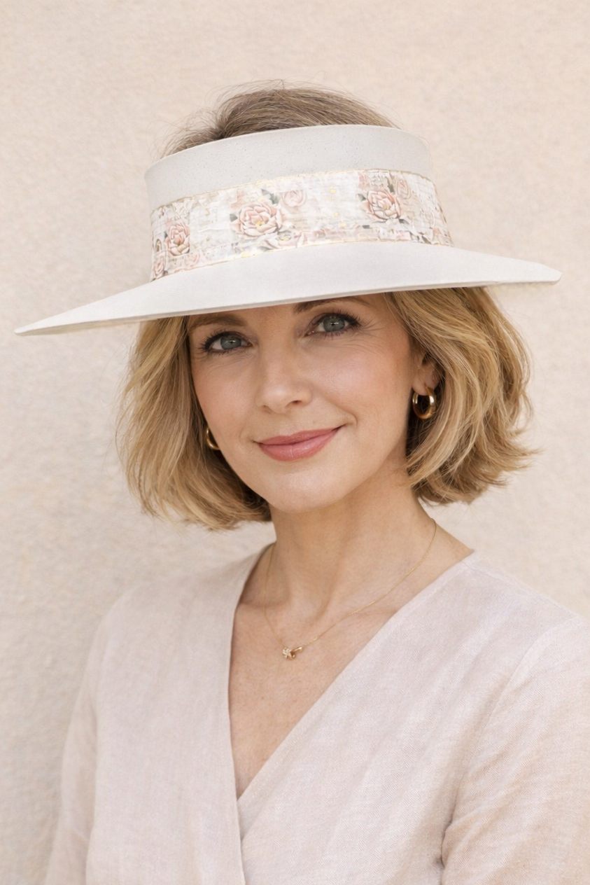 Woman wearing a white visor with floral details against a beige background