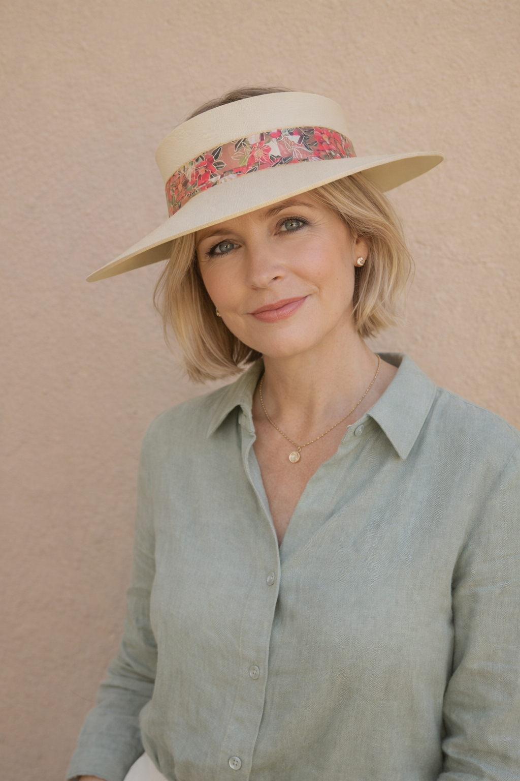 Woman wearing a wide-brimmed hat with a floral band against a beige background