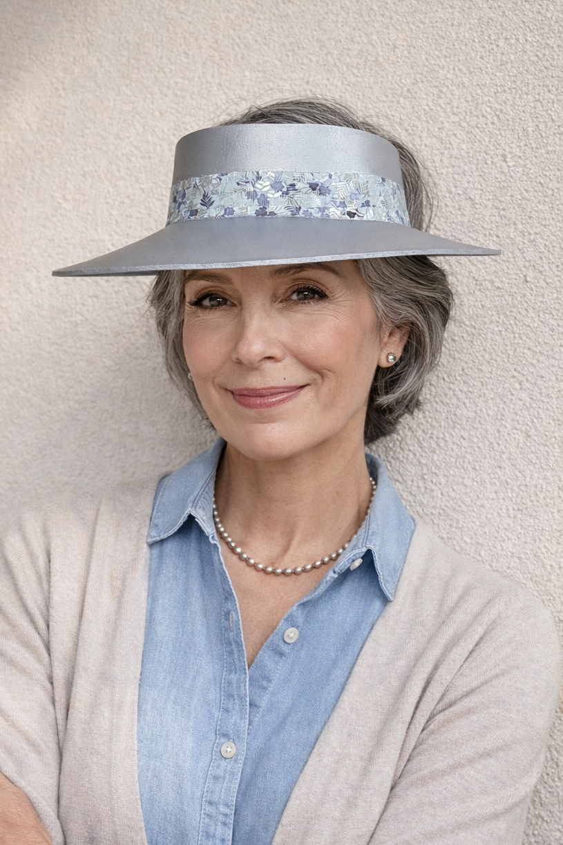 Woman wearing a light blue visor hat with floral embellishments against a neutral background