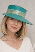 Woman wearing a teal hat with a patterned band against a neutral background