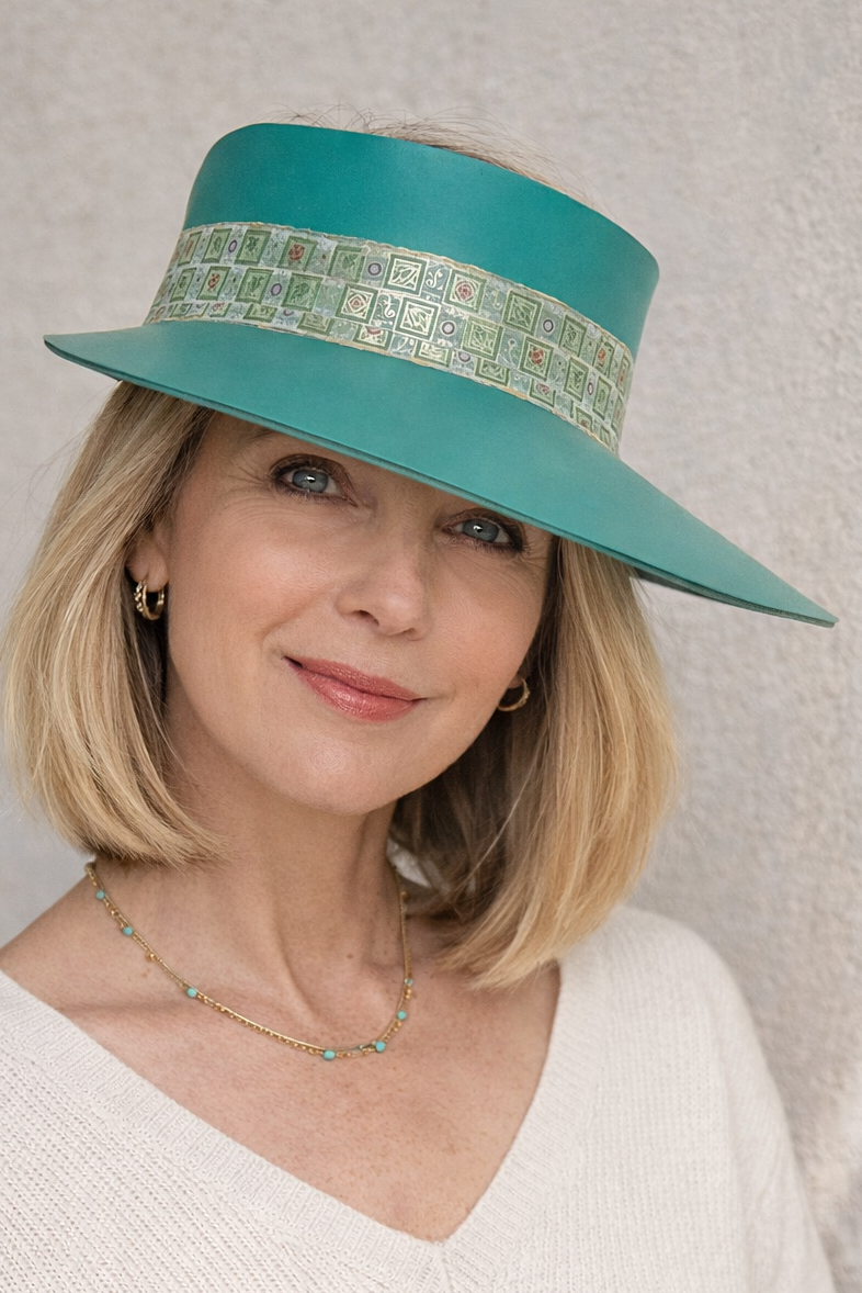 Woman wearing a teal hat with a patterned band against a neutral background