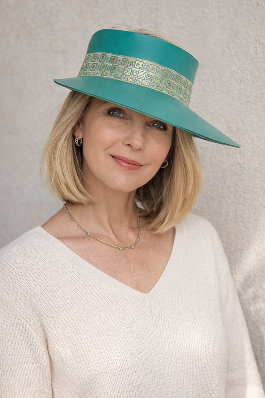 Woman wearing a teal hat with a patterned band against a neutral background