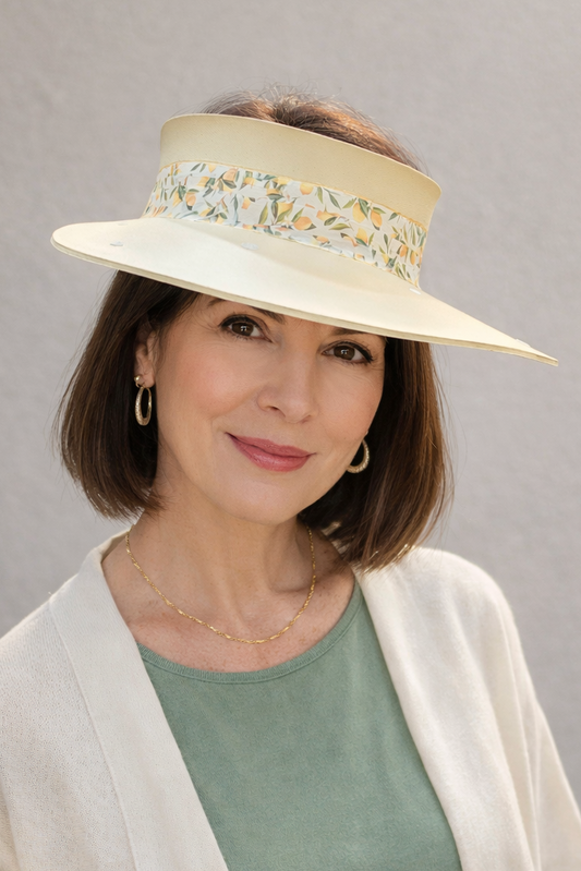Woman wearing a wide-brimmed hat with floral details against a plain background