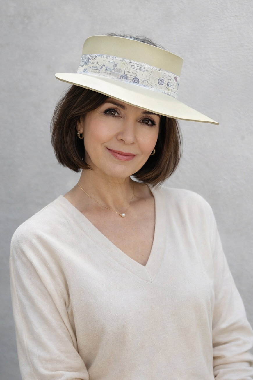 Woman wearing a cream-colored hat with a patterned band against a gray background