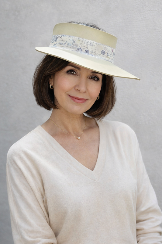 Woman wearing a cream-colored hat with a patterned band against a gray background