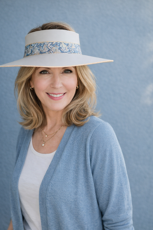 Woman wearing a wide-brimmed hat with a floral band against a blue background